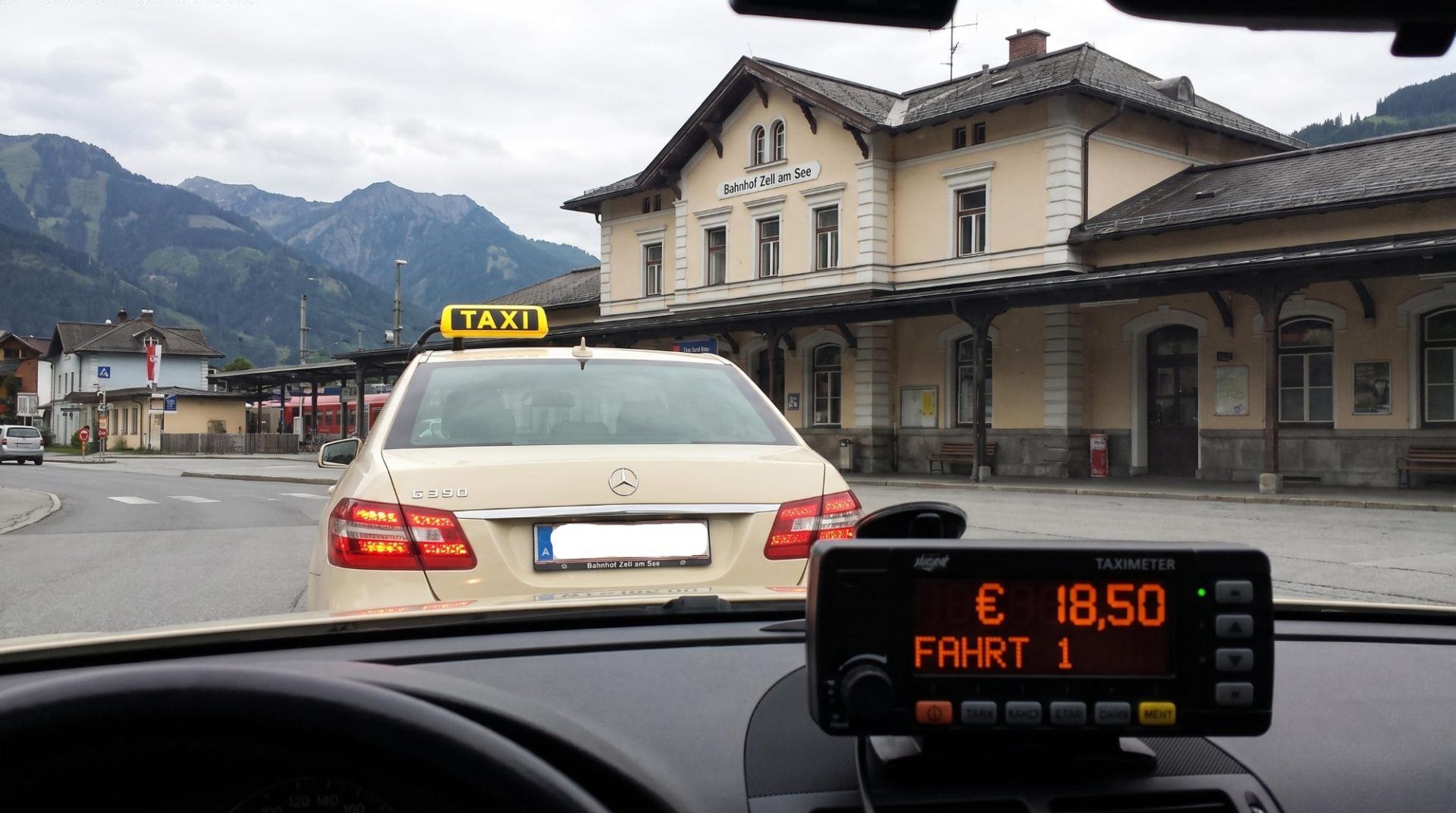 Blick aus einem TOP TAXI zum Bahnhof Zell am See mit den Alpen in der Ferne